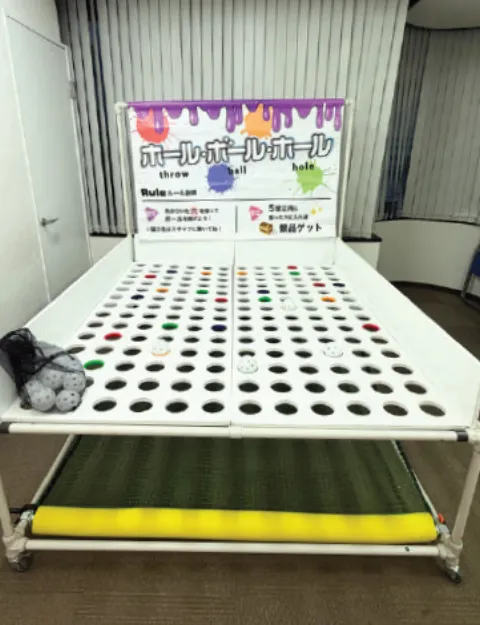 穴がたくさん空いた台と、遊び方を書いた看板